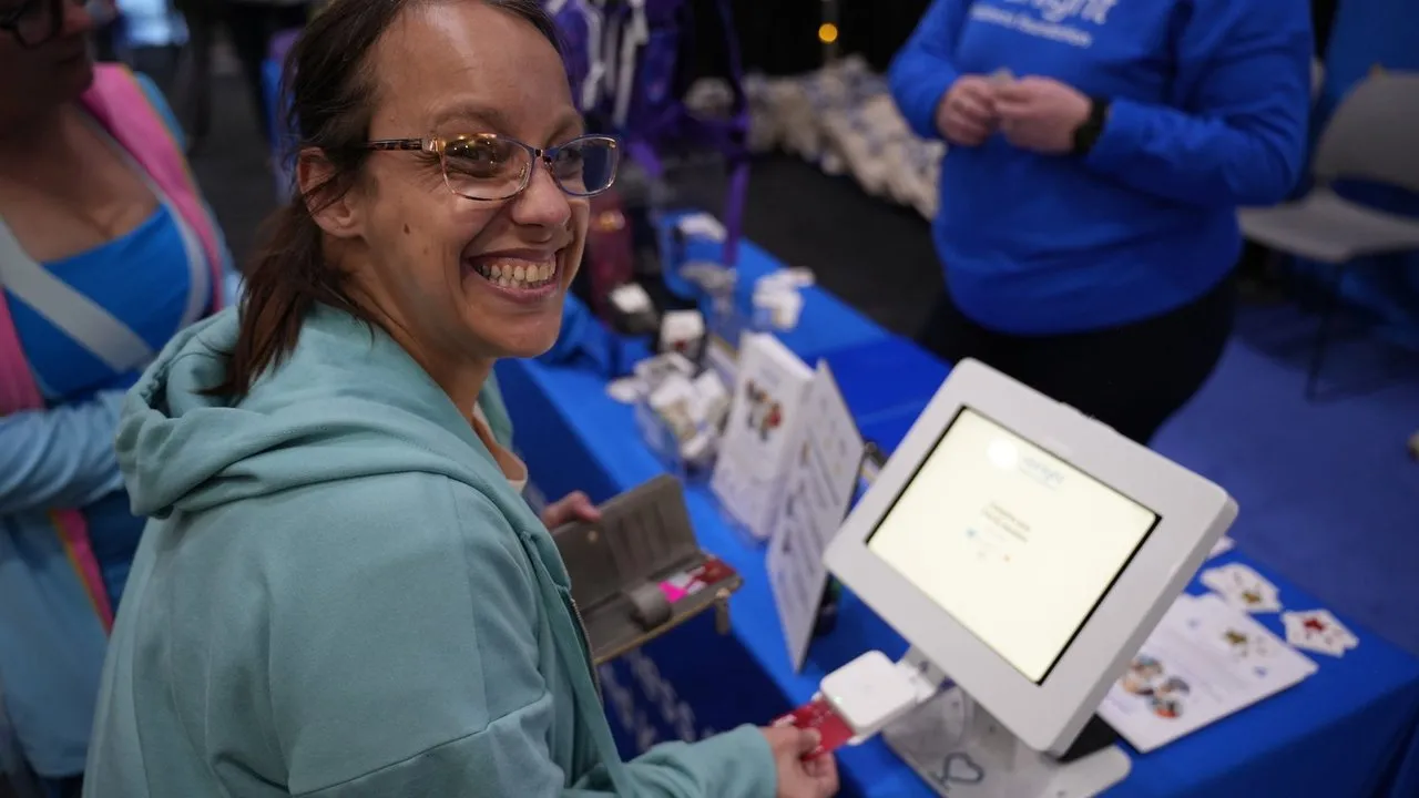 A smiling donor inserting her card at a Tabletop kiosk at a fundraising event